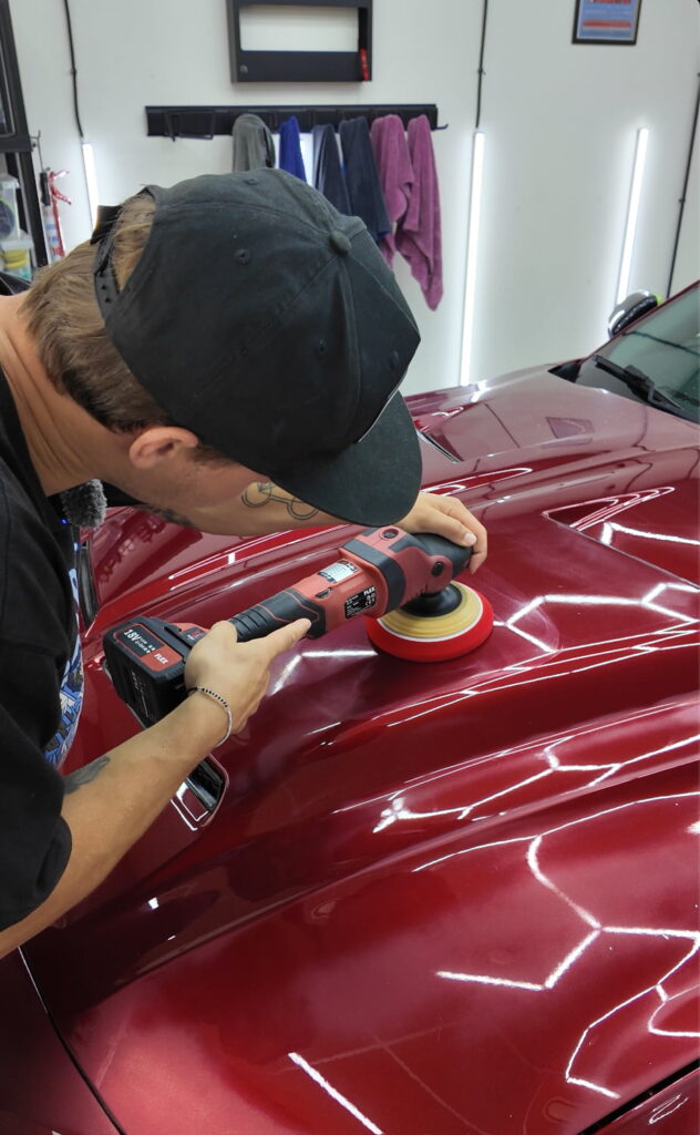 Man polishing red car hood