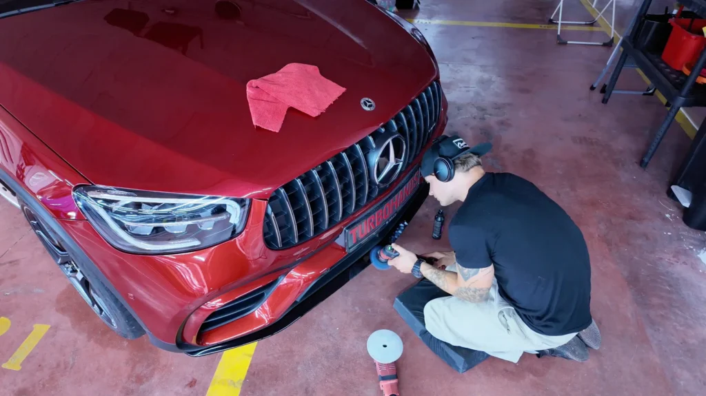 Detailer polishing luxury red car.
